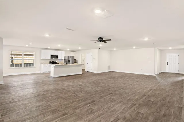 an empty room with wooden floor and a ceiling fan