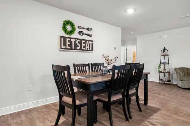 a living room with furniture and a dining table with wooden floor