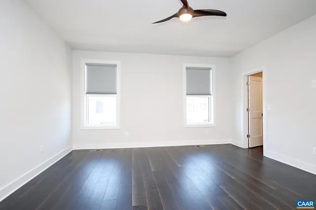 an empty room with wooden floor cabinet and windows