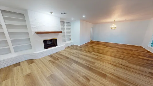 a view of empty room with a fireplace and wooden floor