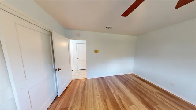 a view of a room with wooden floor and a ceiling fan