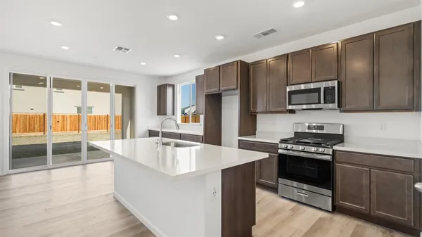 a kitchen with kitchen island granite countertop a sink stove and refrigerator