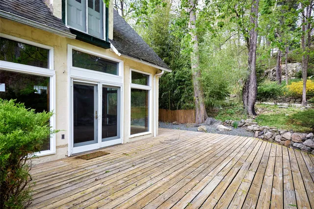 a view of a house with brick walls plants and large tree