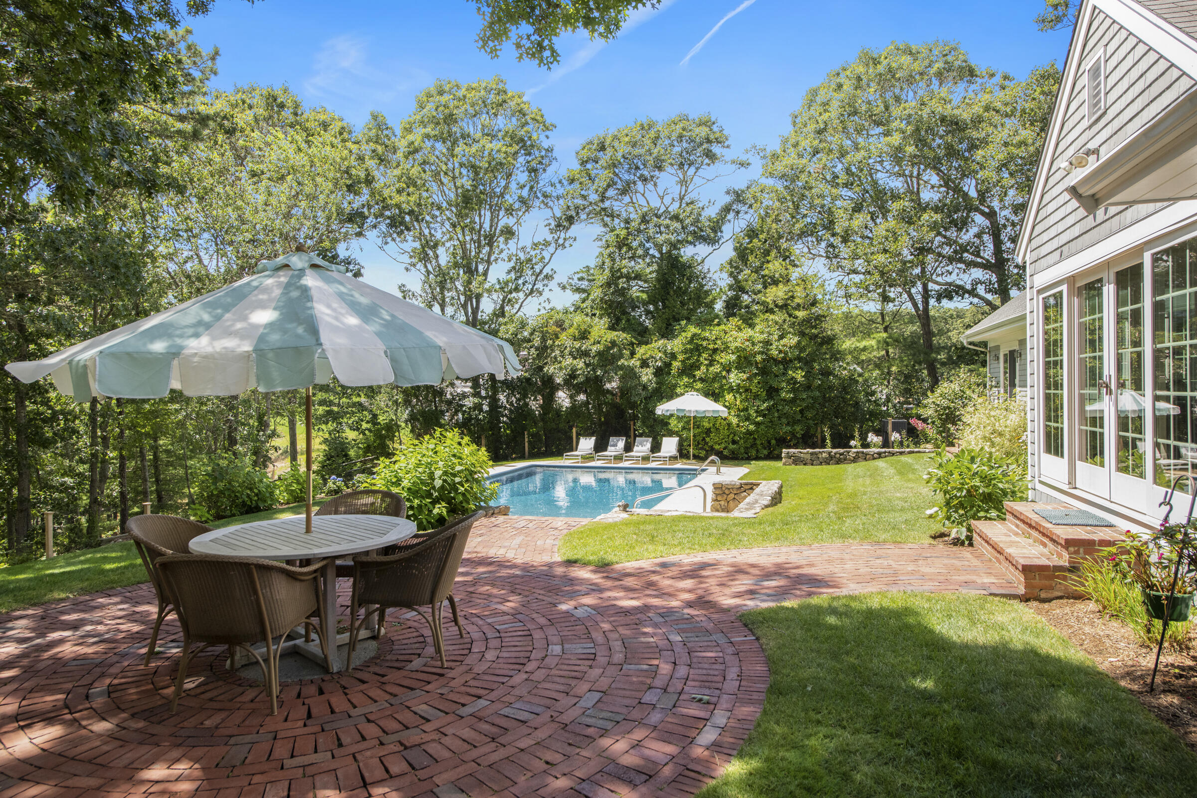 175 Starboard Lane Osterville, MA 02655 - Photo 5 of 39 a view of a swimming pool with a table and chairs under an umbrella