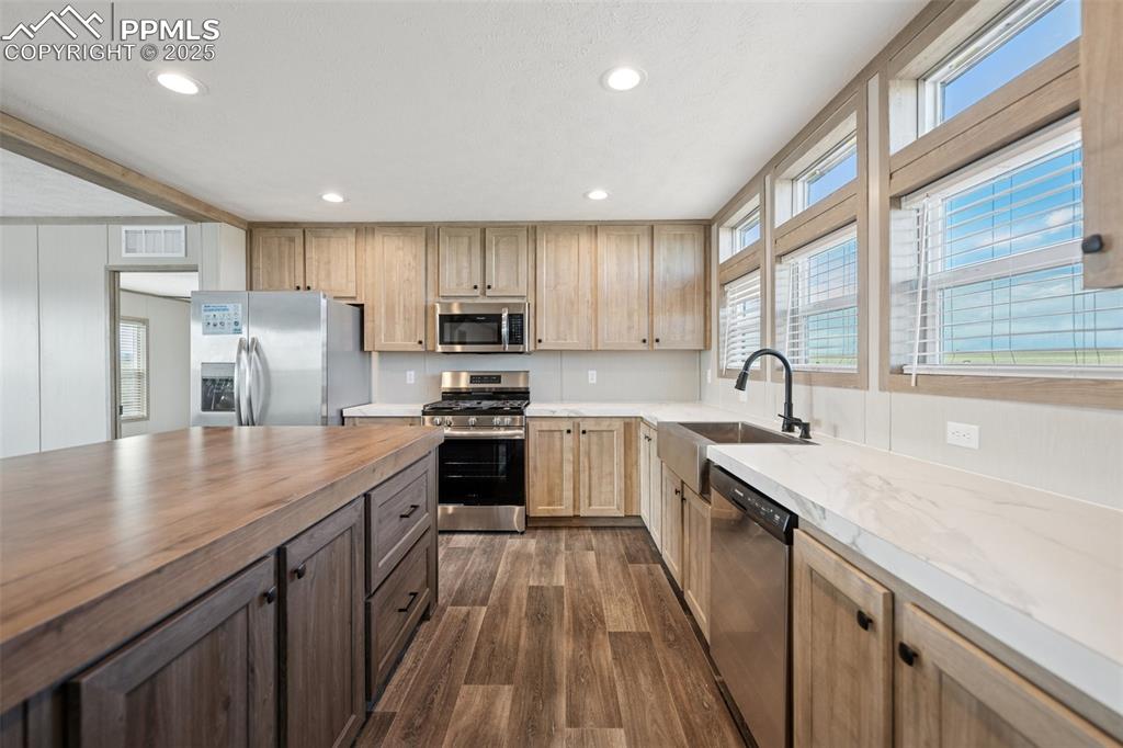 30495 Darroll Drive Yoder, CO 80864 - Photo 30 of 34 a kitchen with stainless steel appliances granite countertop a sink a stove a refrigerator cabinets and a kitchen island