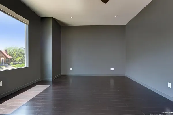 an empty room with wooden floor and windows