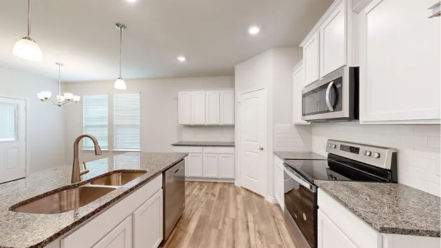 a kitchen with granite countertop a stove a sink and a microwave