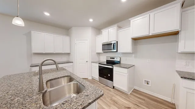a kitchen with kitchen island granite countertop a sink a counter top space and cabinets