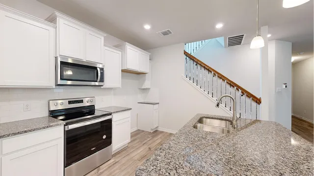 a kitchen with stainless steel appliances granite countertop a sink a stove and a wooden floors
