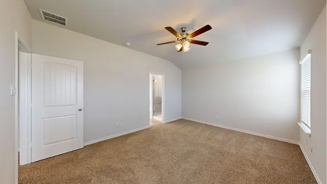 an empty room with a chandelier fan and windows