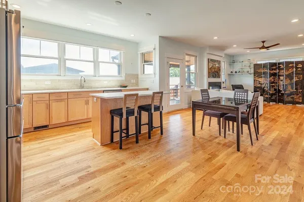 a dining hall with stainless steel appliances granite countertop a stove and kitchen view with wooden floor