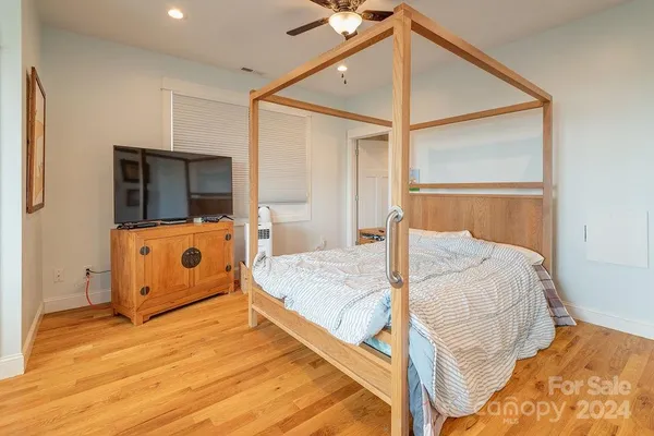 a bed room with a bed a mirror and a wooden floor