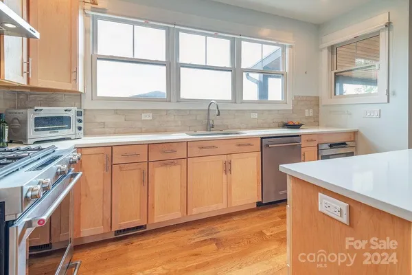 a kitchen with stainless steel appliances granite countertop a stove a sink and a microwave