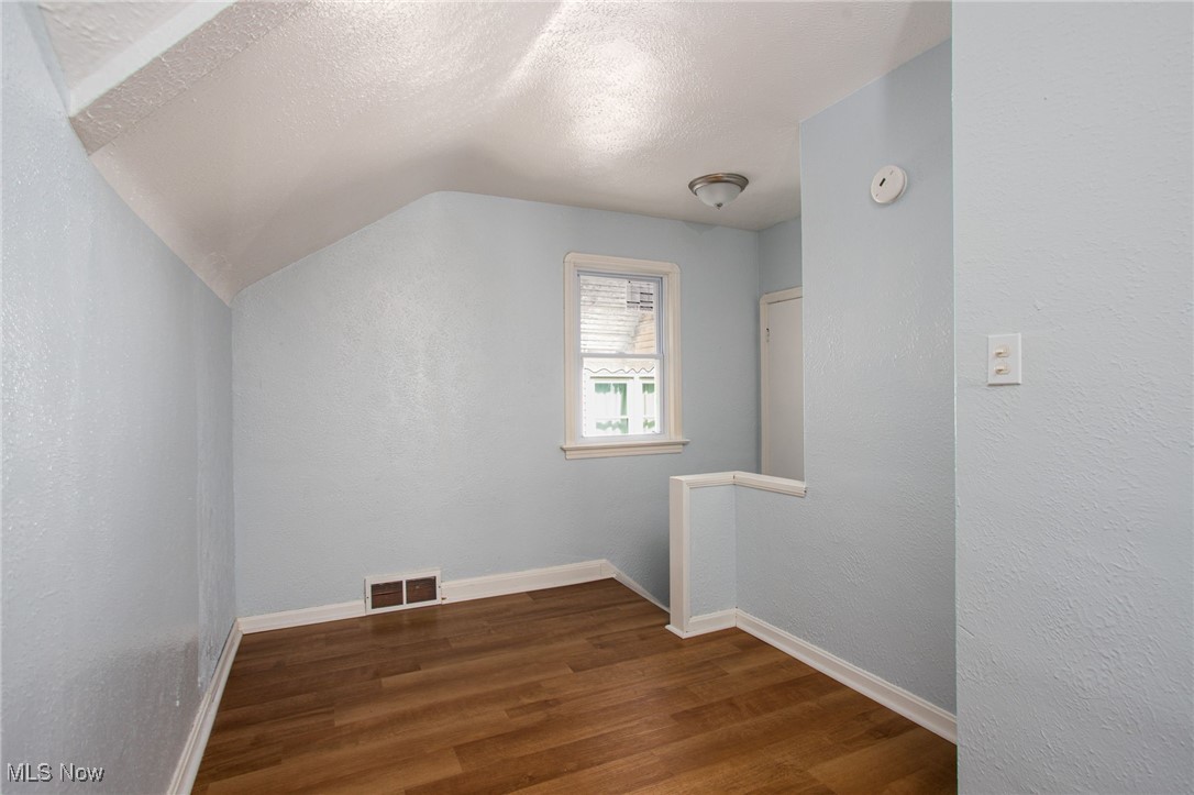 12028 Triskett Road Cleveland, OH 44111 - Photo 18 of 23 Bonus room with dark wood-style floors, a textured ceiling, and vaulted ceiling
