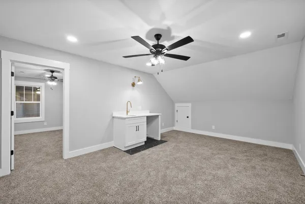 a view of a livingroom with a ceiling fan a kitchen space and a sink