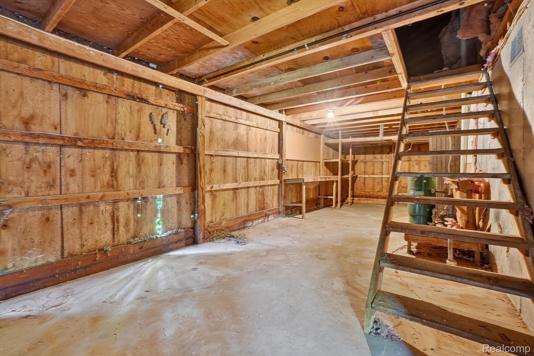 3760 Webberville Road North Williamston, MI 48895 - Photo 43 of 80 Utility space featuring a concrete floor, exposed wooden ceiling joists, wood paneling, built-in shelving, and a wooden staircase