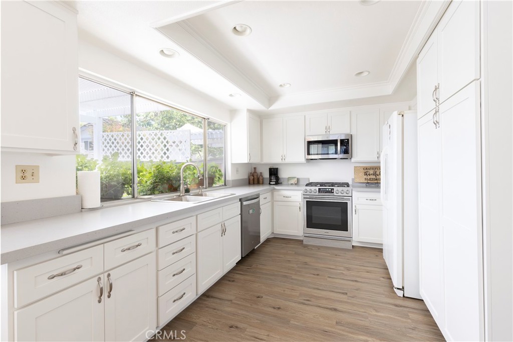 94 Wildwood, Unit 11 Irvine, CA 92604 - Photo 8 of 41 a kitchen with granite countertop white cabinets and white appliances