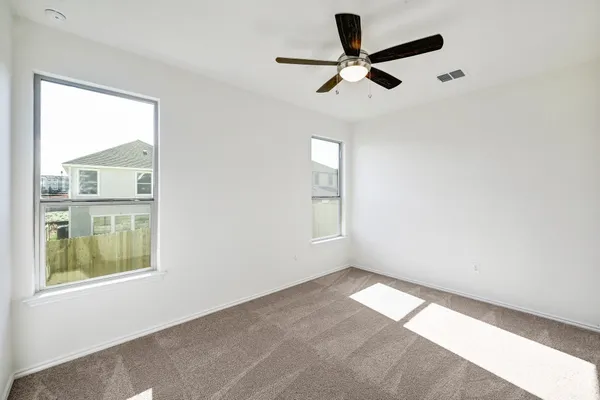 an empty room with windows and ceiling fan