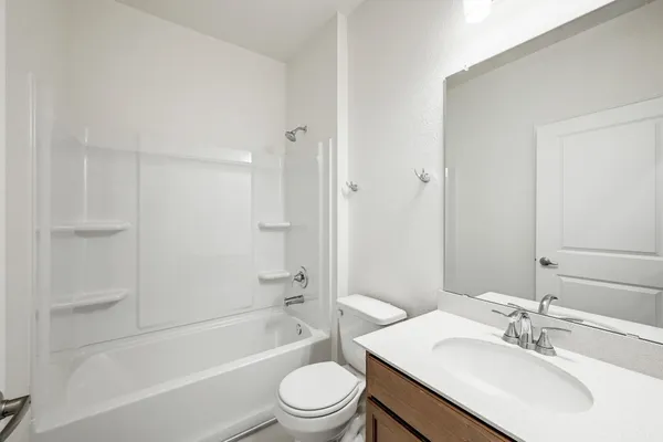 a bathroom with a bathtub shower sink vanity mirror and toilet