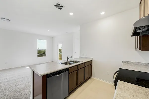 a kitchen with a sink dishwasher and a stove with wooden floor