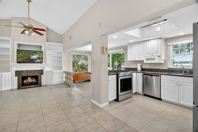 a kitchen with stainless steel appliances granite countertop white cabinets and a window