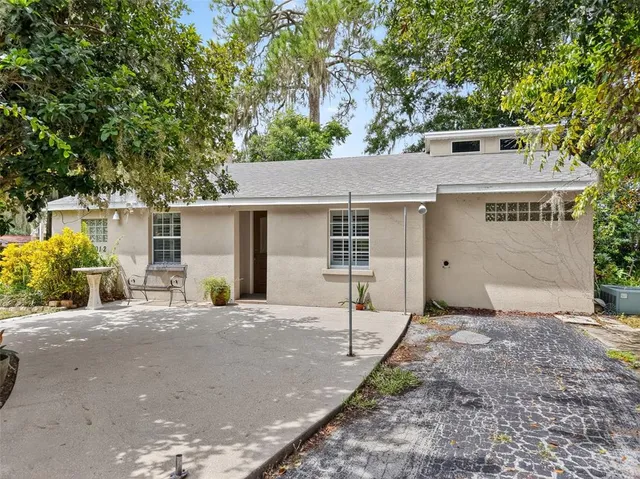 a front view of a house with yard and trees in the background
