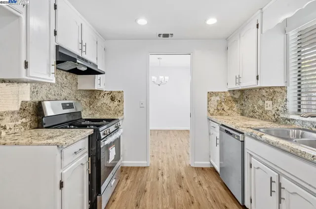 a kitchen with stainless steel appliances granite countertop a sink stove and cabinets
