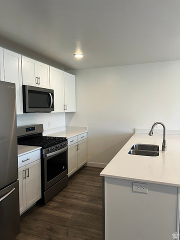 562 Hal Street, Unit 152 Tooele, UT 84074 - Photo 33 of 44 Contemporary kitchen featuring white cabinetry, light-toned countertops, stainless steel appliances, and wood-finish flooring
