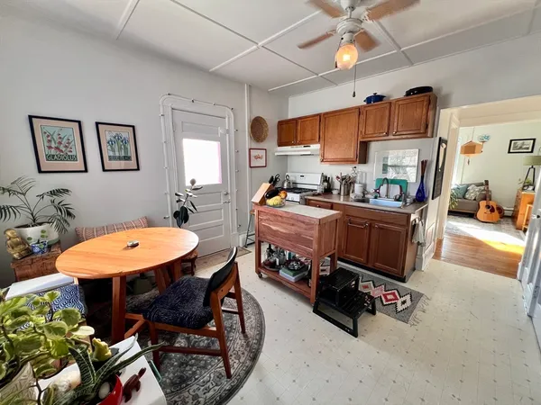 a room with stainless steel appliances a stove a kitchen island a sink dishwasher a dining table and chairs with wooden floor