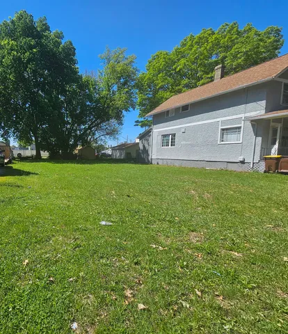 a house that is sitting in the grass with large trees