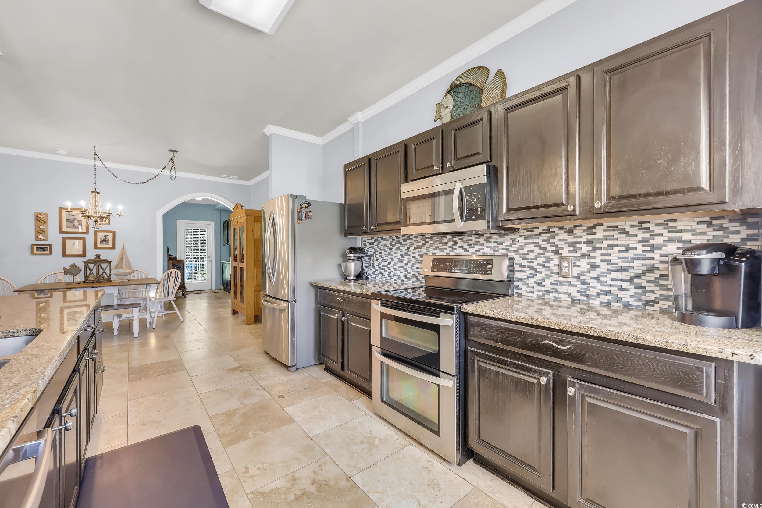 4536 Fringetree Drive Murrells Inlet, SC 29576 - Photo 3 of 40 Kitchen with appliances with stainless steel finishes, arched walkways, tasteful backsplash, ornamental molding, and dark brown cabinetry