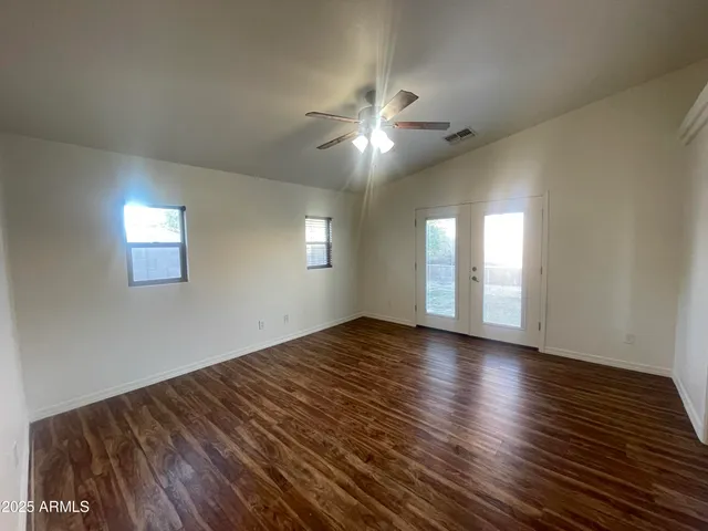 a view of empty room with wooden floor and fan