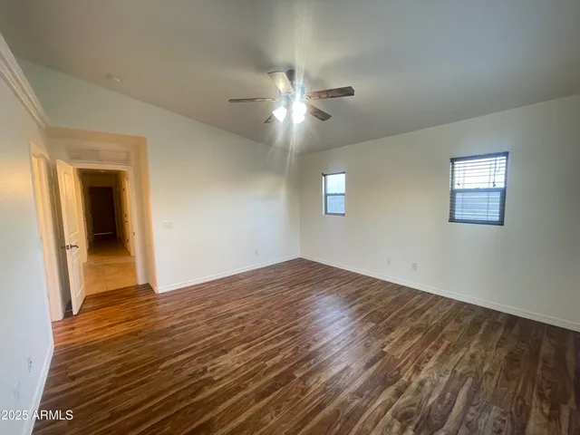 a view of empty room with wooden floor and fan