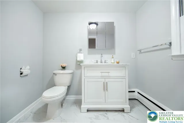 a bathroom with a toilet sink vanity and mirror