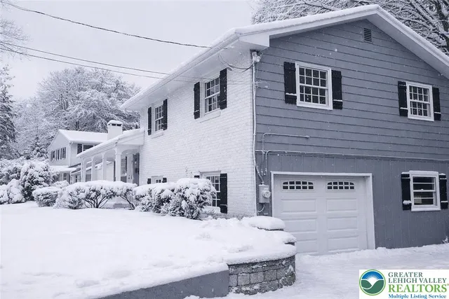 a front view of a house with snow on the road