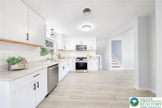 a large kitchen with granite countertop white cabinets and white appliances