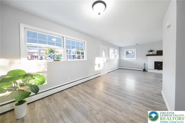 a view of an empty room with a window and wooden floor