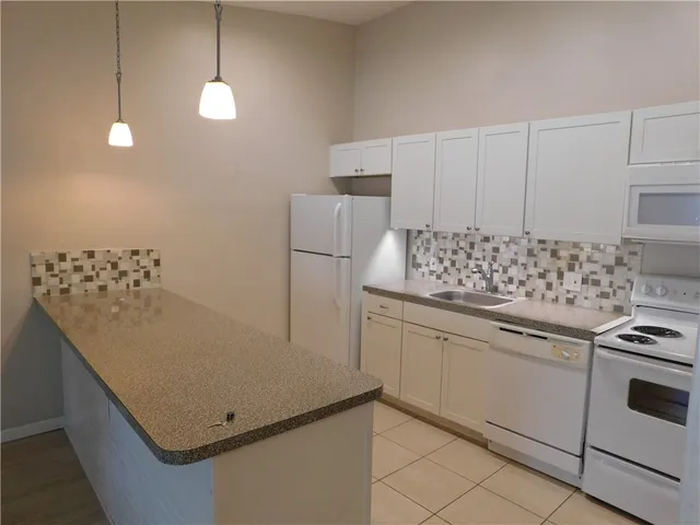a kitchen with granite countertop white cabinets and white appliances