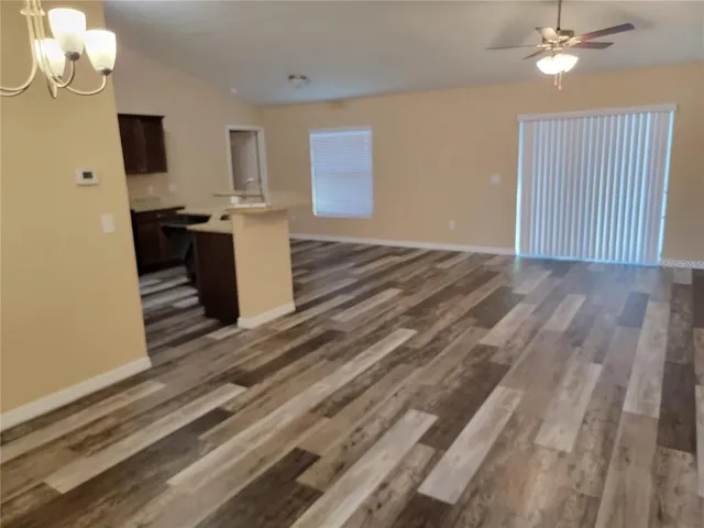 a view of kitchen and empty room with wooden floor