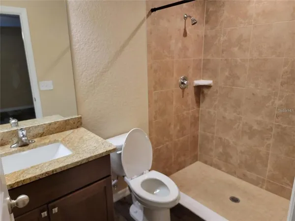 a bathroom with a granite countertop sink toilet and shower