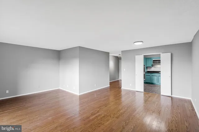 a view of an empty room with wooden floor and a window