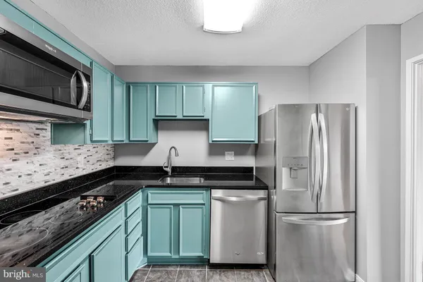 a kitchen with granite countertop a refrigerator and a stove top oven