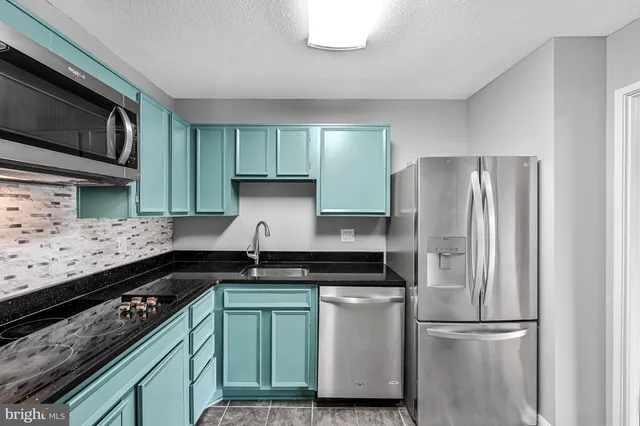 a kitchen with granite countertop a refrigerator and a stove top oven