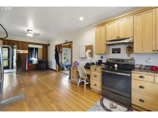 a kitchen with stainless steel appliances a stove a sink dishwasher and a dining table with wooden floor