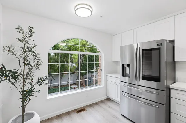 a kitchen with a refrigerator and countertop white cabinets