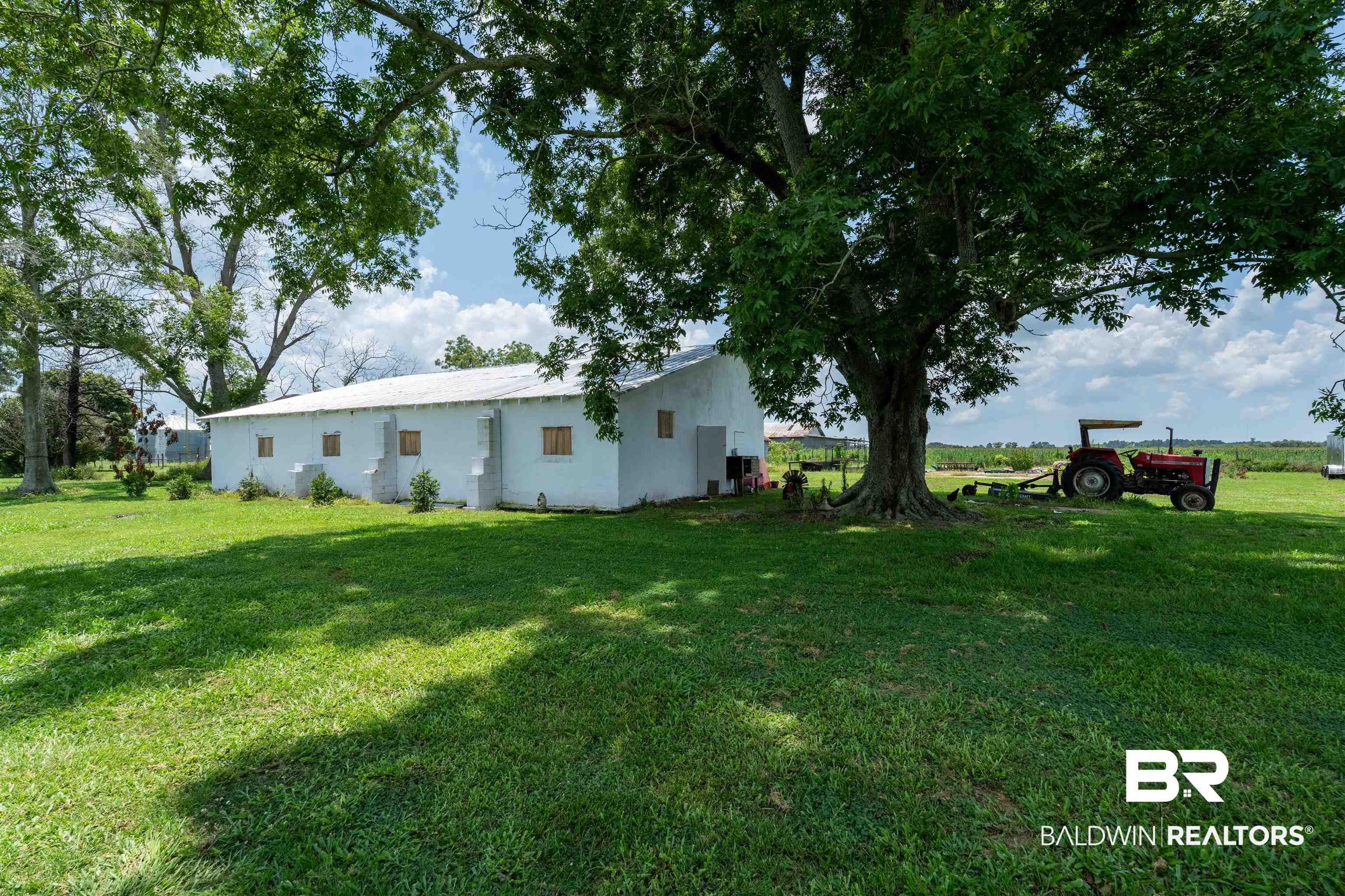 15575 Mikkelsen Road Summerdale, AL 36580 - Photo 25 of 68 Expansive grassy area with mature shade trees, bordering a white-sided outbuilding with multiple window openings