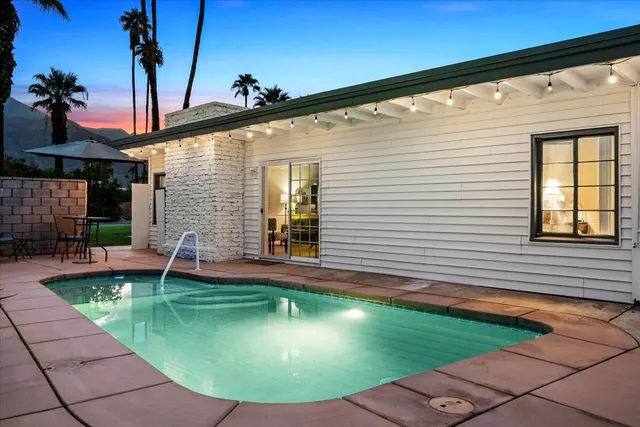 a backyard of a house with table and chairs under an umbrella