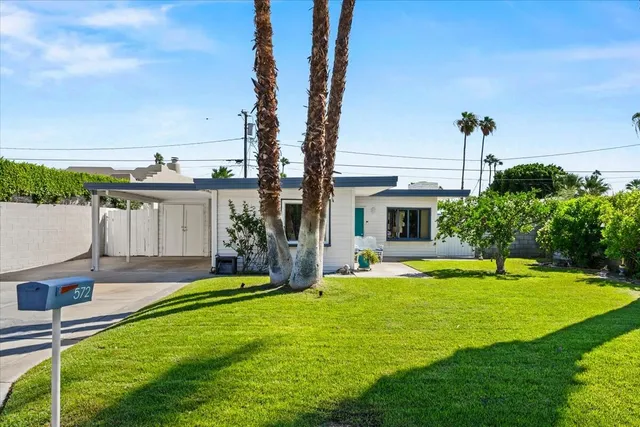 a view of a house with a yard and a large tree