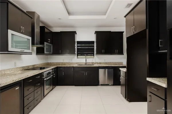 a large kitchen with stainless steel appliances granite countertop a stove a sink and a microwave