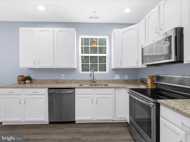 a kitchen with stainless steel appliances granite countertop a sink dishwasher a stove and a microwave oven with cabinets